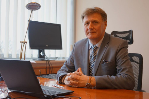 Dyrektor Generalny Jacek Wiśniewski siedzi przy biurku przy komputerze w swoim gabinecie, patrzy na wsprost, ubrany w szary garnitur