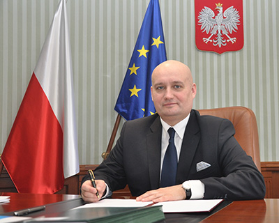 Zbigniew Hoffmann na tle flagi polskiej i unijnej