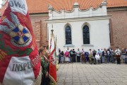 Widok zza sztandaru na uczestników uroczystości. 