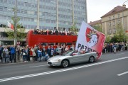 kabriolet z flagą przejeżdża na tle czerwonego autobusu