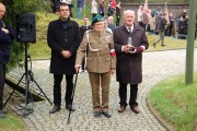 Pułkownik Jan Podhorski idzie z asystą złożyć znicz. 