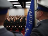 Widok siedzących policjantów zza pocztu sztandarowego