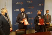 Wojewoda oraz starosta powiatu ostrowskiego trzymają w rękach podpisane umowy