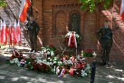 Złożone kwiaty pod tablicą pamiątkową