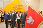 Goście uroczystości stoją w sali gimnastycznej.