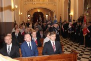 Uczestnicy mszy siedzą w ławach kościelnych. 