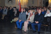 Wojewoda wraz z innymi uczestnikami siedzi w ławie podczas mszy. 