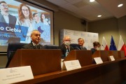 Uczestnicy konferencji siedzą za stołem prezydialnym