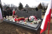 Pomnik nogrobny i ustawione wokół polskie flagi.