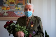 Eugeniusz Kubacki pozuje do zdjęcia z bukietem czerwonych róż