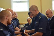 Zastępca komendanta wojewódzkiego Policji w Poznaniu wręcza nagrodę. 