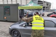 Przedstawiciel Wojsk Obrony Terytorialnej wskazuje kierowcy samochodu drogę na badanie
