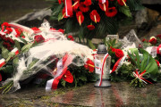 Kwiaty i znicze położone pod pomnikiem w parku Zamkowym