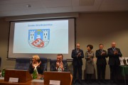 Nagrodzeni samorządowcy i wicewojewoda stoją na tle slajdu z herbem Wągrowca.