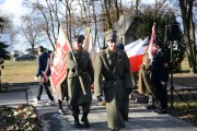 Trzech rekonstruktorów w mundurach z epoki niesie sztandar