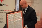 Wojewoda trzyma kopię nadania Piłsudskiemu godności doktora honorowego Uniwersytetu Poznańskiego.