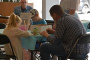 Dzieci i dorośli malują przy stoliku. 