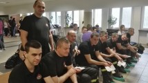 Grupka młodych mężczyzn siedzi na krzesłach oczekując na swoją kolej do oddawania krwi.
