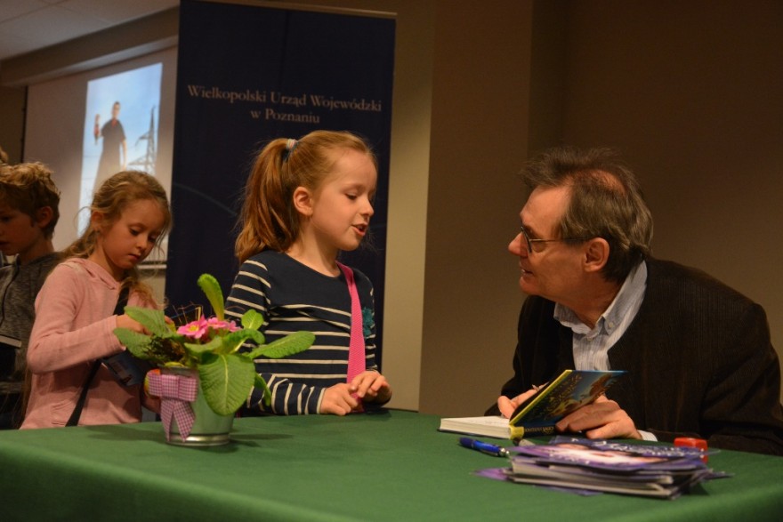Andrzej Maleszka podpisuje dziewczynce swoją książkę. 
