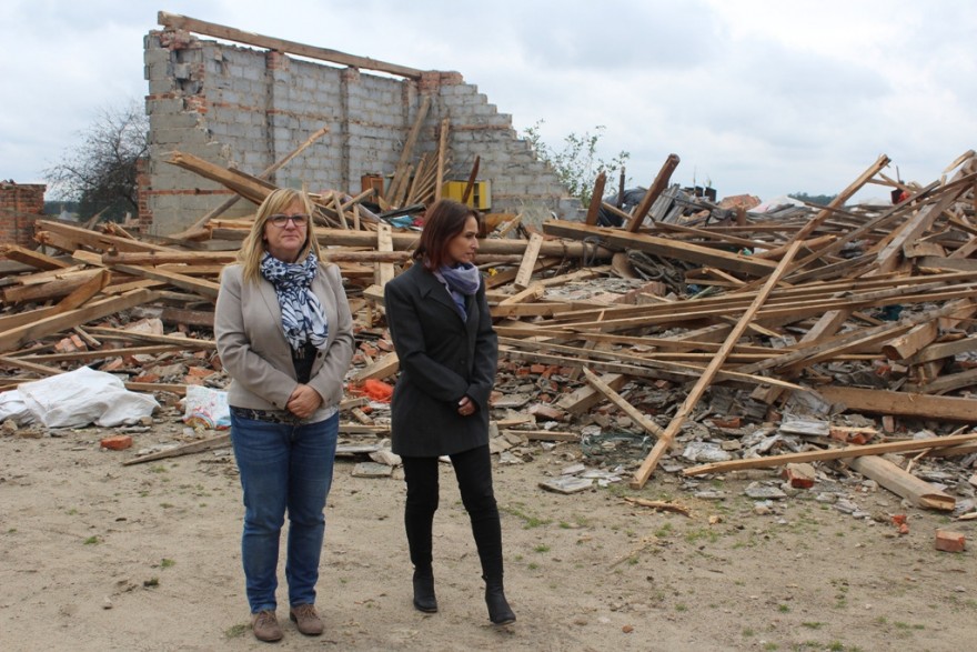 Urzędnicy z Wydziału Polityki Społecznej WUW na tle zniszczonego budynku.