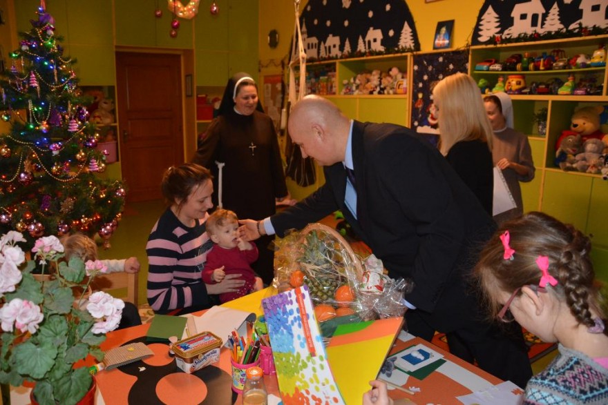 Wojewoda przekazuje prezenty i wita się z małą dziewczynką. 