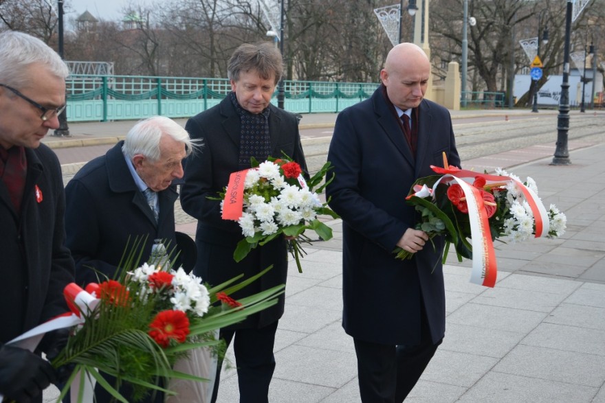 Wojewoda składa kwiaty przed tablicą.