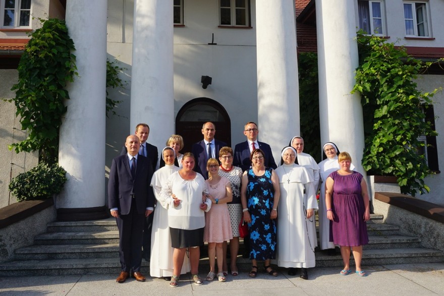 Wspólne zdjęcie wojewody z mieszkańcami domu przed wejściem do budynku.