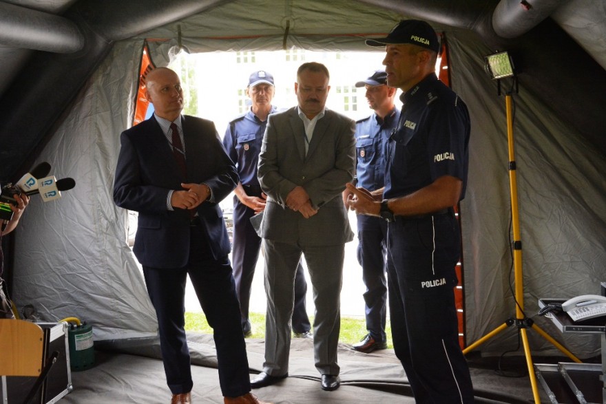 Wojewoda z zastępcą komendanta wojewódzkiego policji w Poznaniu rozmawia w przekazywanym namiocie.  