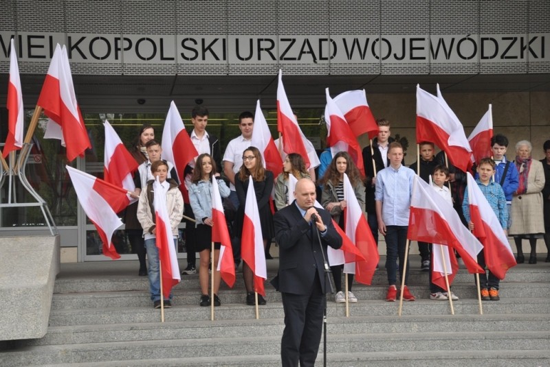 Wojewoda na tle flag biało-czerwonych.