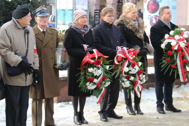 Uczestnicy uroczytości z kwiatami przed tablicą pamiątkową.